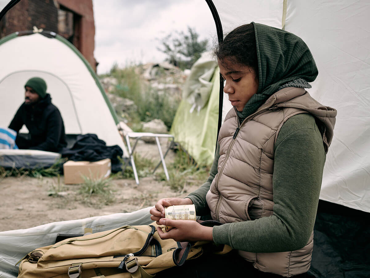 hungry-african-girl-holding-canned-food-while-sitting.jpg